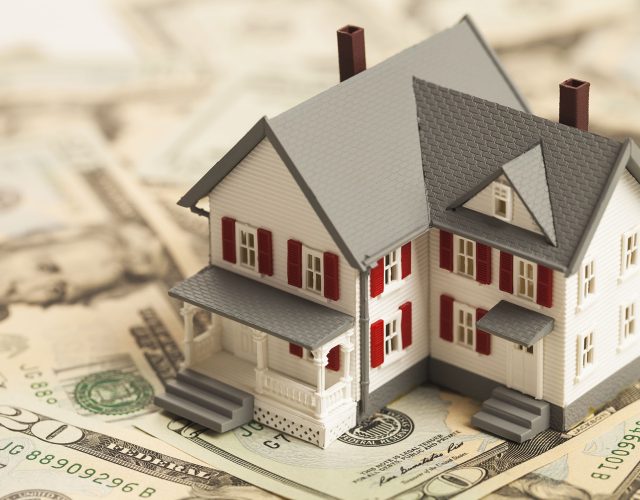 Single family house on pile of money. Concept of real estate.